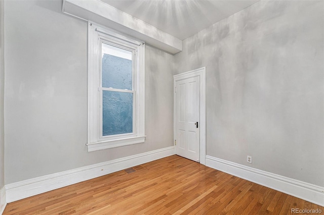 spare room with baseboards and light wood-style floors