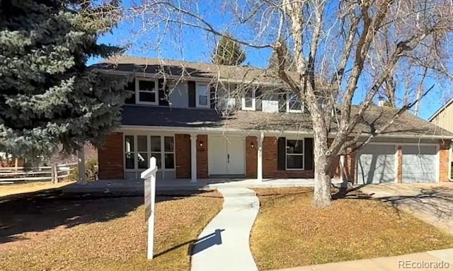 traditional home featuring a porch, concrete driveway, fence, and a garage