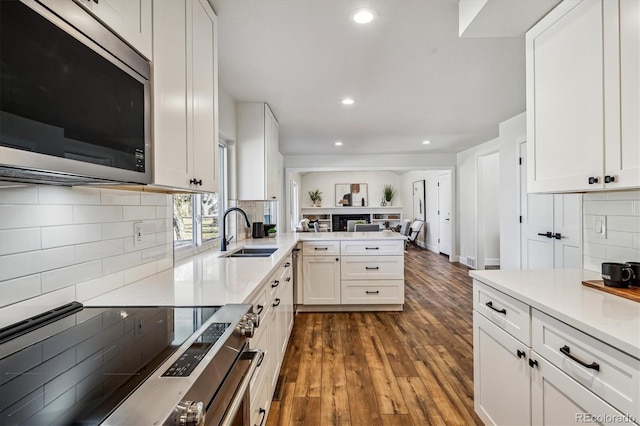 kitchen featuring white cabinetry, a peninsula, stainless steel appliances, and a sink