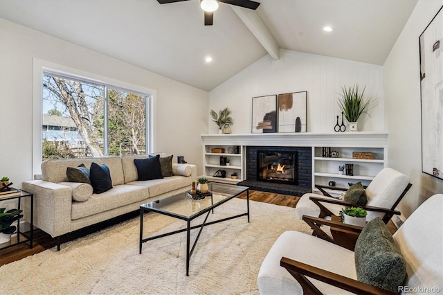 living area with a fireplace, lofted ceiling with beams, a ceiling fan, and wood finished floors