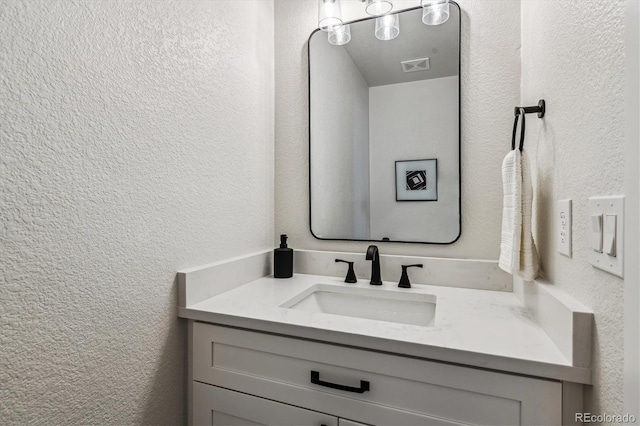 bathroom with visible vents, vanity, and a textured wall