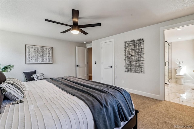 bedroom featuring ensuite bathroom, a textured ceiling, carpet floors, baseboards, and ceiling fan