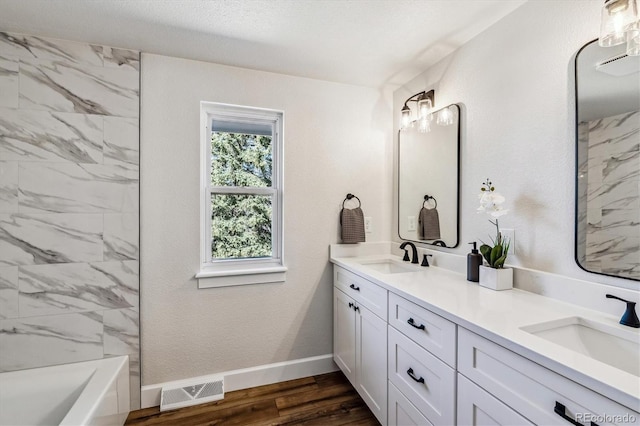 bathroom featuring visible vents, wood finished floors, baseboards, and a sink