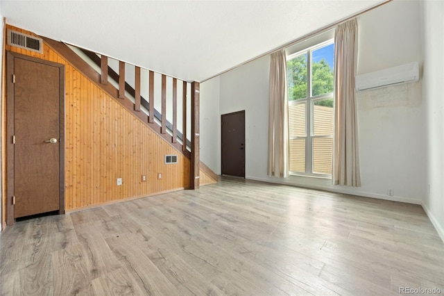 3550 S Harlan St Unit 363, Denver, CO 80235 - unfurnished living room with an AC wall unit, wood walls, light wood-type flooring, and stairway