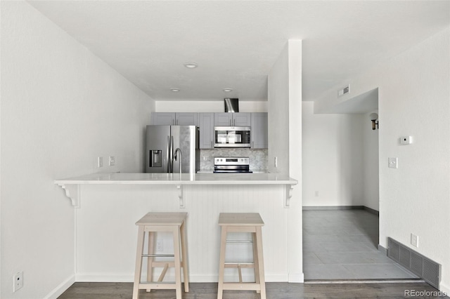 3550 S Harlan St Unit 363, Denver, CO 80235 - kitchen featuring appliances with stainless steel finishes, gray cabinets, a peninsula, and a breakfast bar
