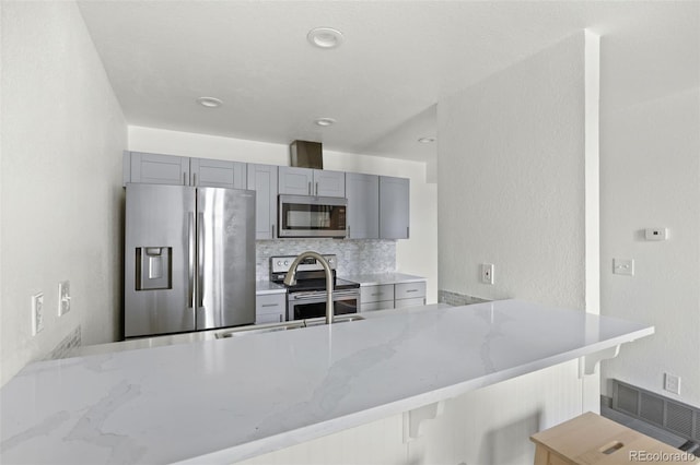 3550 S Harlan St Unit 363, Denver, CO 80235 - kitchen with appliances with stainless steel finishes, a peninsula, gray cabinets, light stone counters, and a textured wall