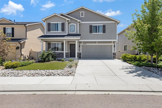 10869 Traders Pkwy, Fountain, CO 80817 - view of front of property featuring a garage, concrete driveway, stone siding, covered porch, and a front lawn