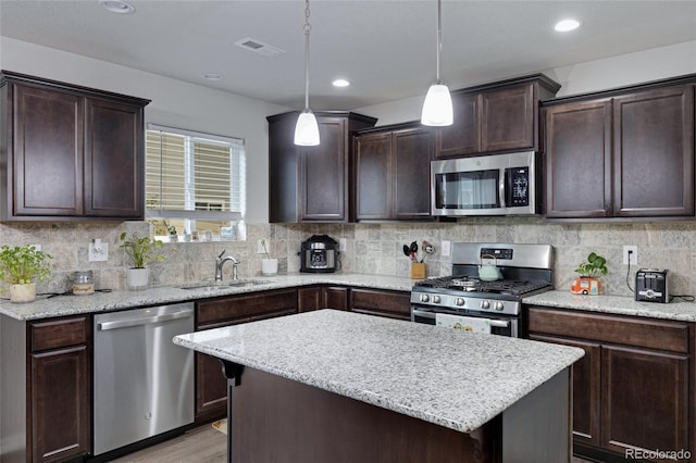 10869 Traders Pkwy, Fountain, CO 80817 - kitchen featuring appliances with stainless steel finishes, a sink, dark brown cabinetry, decorative backsplash, and light wood-type flooring