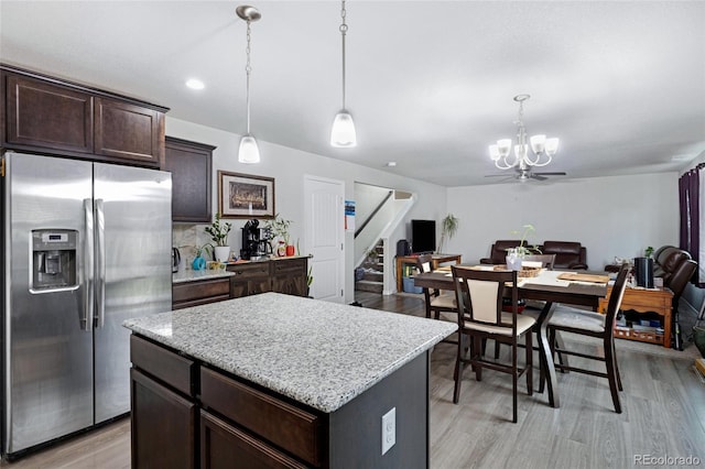 10869 Traders Pkwy, Fountain, CO 80817 - kitchen with stainless steel fridge, a chandelier, dark brown cabinets, open floor plan, and a center island
