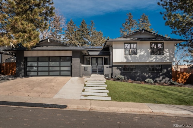 split level home featuring concrete driveway, an attached garage, fence, a front lawn, and brick siding