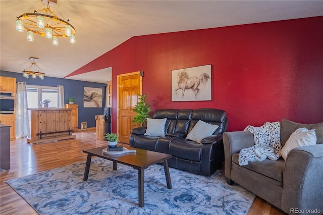 living room with wood finished floors, vaulted ceiling, and an inviting chandelier