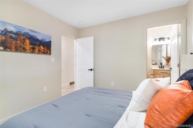 bedroom featuring ensuite bathroom and sink