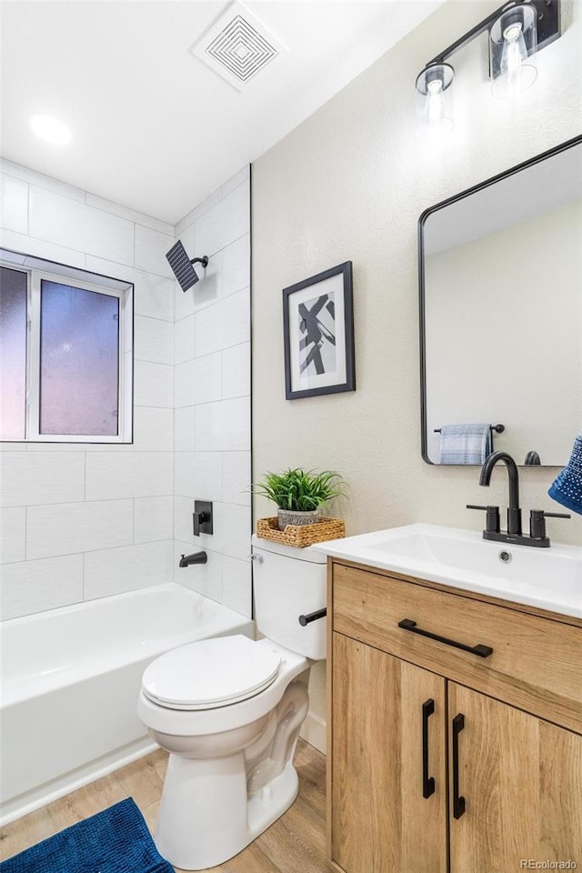 full bathroom with tiled shower / bath, toilet, vanity, and hardwood / wood-style flooring