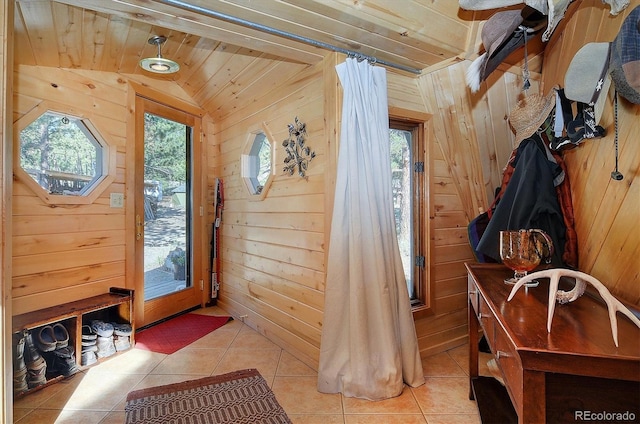 interior space with wood ceiling, lofted ceiling, light tile patterned floors, and wooden walls