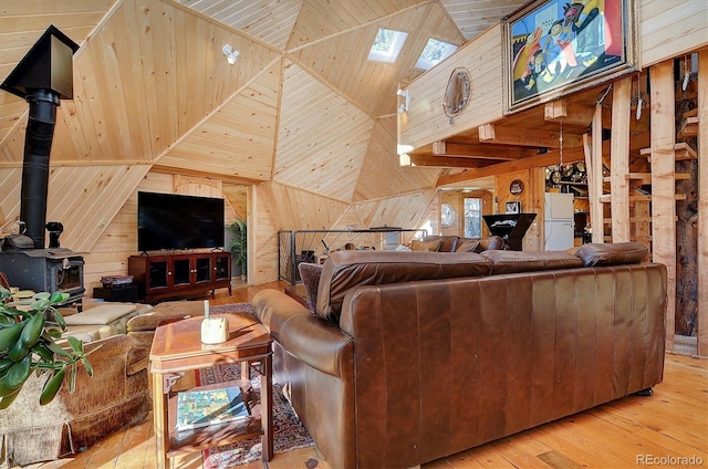 living room with wooden walls, wooden ceiling, a wood stove, light hardwood / wood-style floors, and lofted ceiling