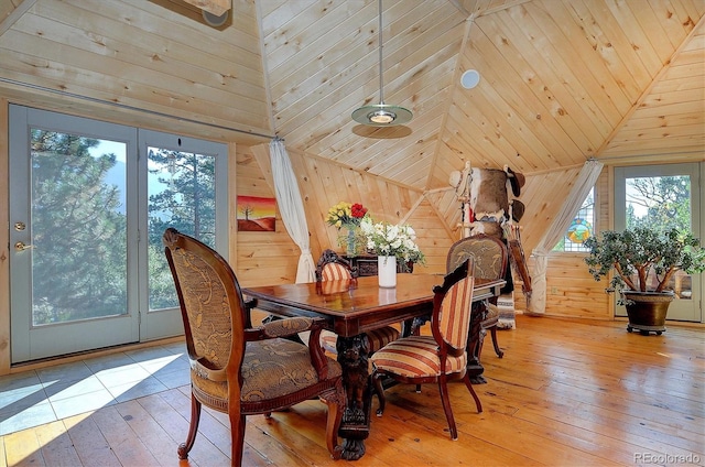 dining area featuring hardwood / wood-style floors, wood walls, and a high ceiling