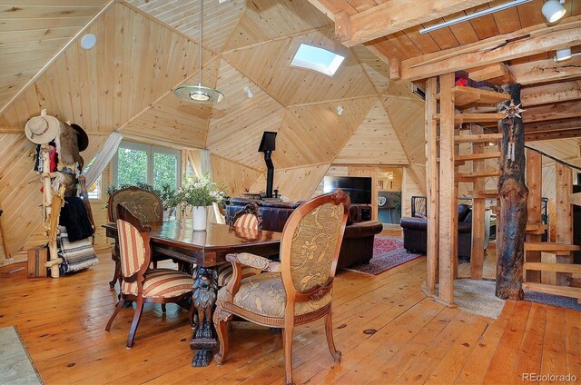 dining space featuring wooden ceiling, wood-type flooring, lofted ceiling with skylight, and wooden walls