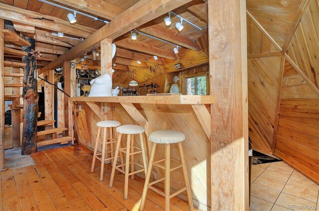 bar with wood-type flooring, wooden walls, beamed ceiling, and wooden ceiling