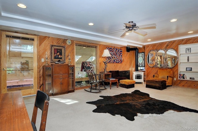 living room with carpet flooring, ceiling fan, and wood walls