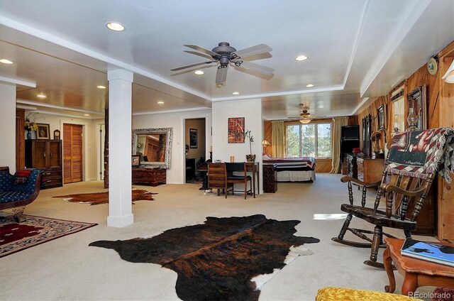 carpeted living room with crown molding, a raised ceiling, ceiling fan, and decorative columns