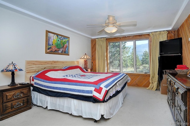 carpeted bedroom with ceiling fan and wood walls