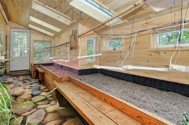 interior space featuring wood ceiling, lofted ceiling with skylight, and wooden walls