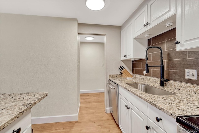 kitchen featuring sink, dishwasher, white cabinetry, light stone countertops, and decorative backsplash