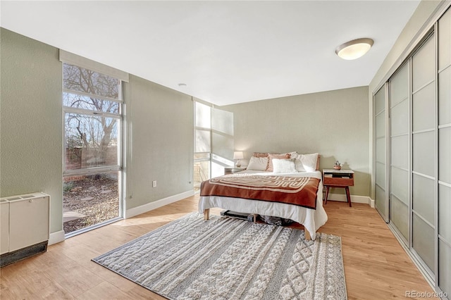 bedroom featuring radiator heating unit, light hardwood / wood-style floors, and a closet