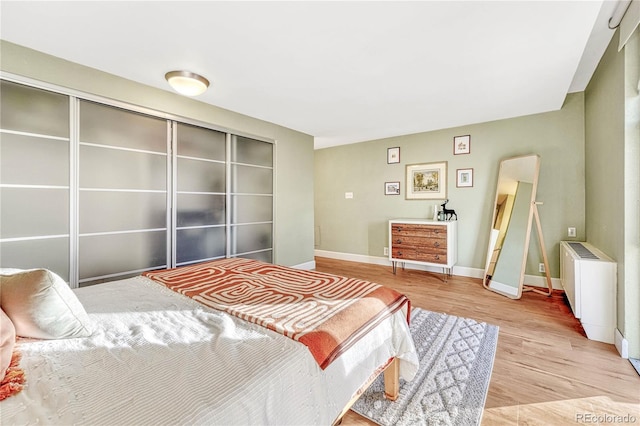 bedroom with radiator, light hardwood / wood-style flooring, and a closet