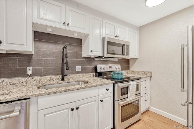 kitchen with sink, tasteful backsplash, light hardwood / wood-style flooring, appliances with stainless steel finishes, and white cabinets