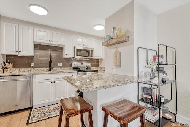 kitchen with light stone counters, sink, stainless steel appliances, and white cabinets