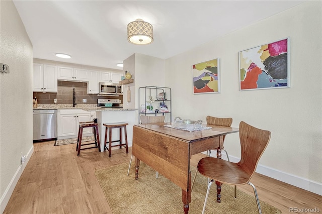 dining area with sink and light wood-type flooring