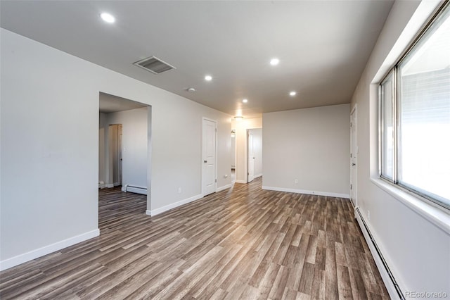 spare room featuring a baseboard heating unit and hardwood / wood-style flooring