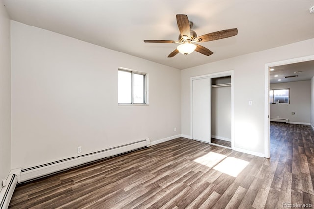 unfurnished bedroom featuring a closet, dark hardwood / wood-style flooring, baseboard heating, and ceiling fan