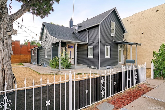 view of front of home featuring a shingled roof, a fenced front yard, and a chimney