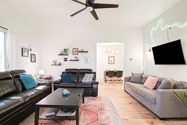 living room with ceiling fan with notable chandelier and light wood-style floors