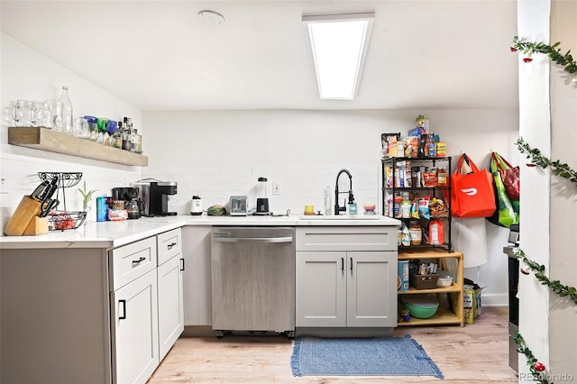 kitchen featuring a sink, open shelves, backsplash, light wood finished floors, and dishwasher