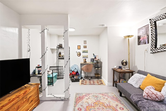 living area featuring baseboards and finished concrete floors