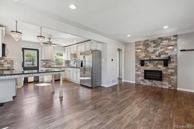 765 Iola St, Aurora, CO 80010 - kitchen with appliances with stainless steel finishes, a large fireplace, decorative backsplash, dark countertops, and a sink