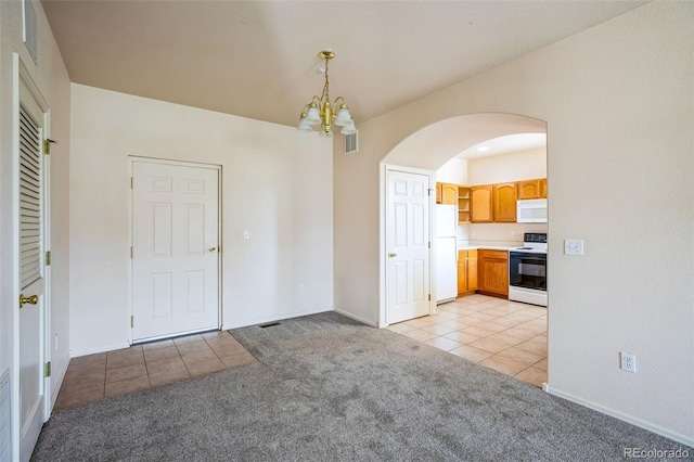 2491 Fountain Greens Blvd Unit B1, Grand Junction, CO 81505 - unfurnished dining area featuring light tile patterned floors, light carpet, arched walkways, and a chandelier