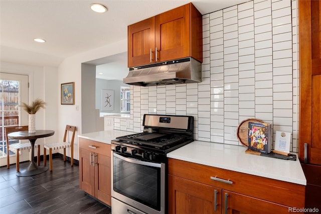 kitchen featuring stainless steel gas stove, tasteful backsplash, and dark wood-type flooring