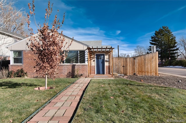 view of front of house featuring a front yard, fence, and brick siding