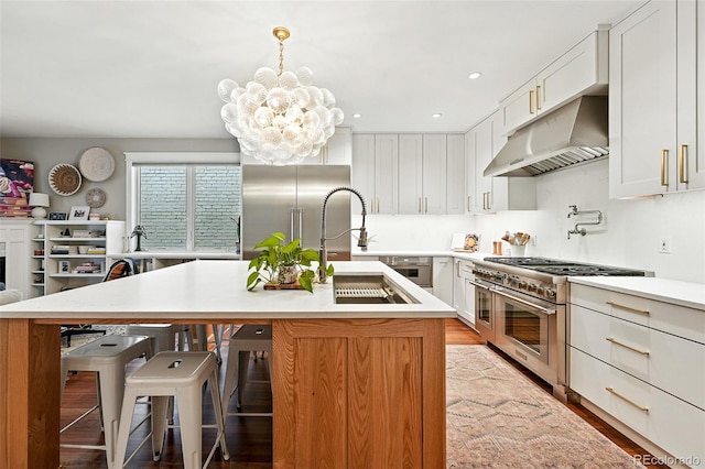 549 Milwaukee St, Denver, CO 80206 - kitchen with high end appliances, range hood, a chandelier, light countertops, and a breakfast bar