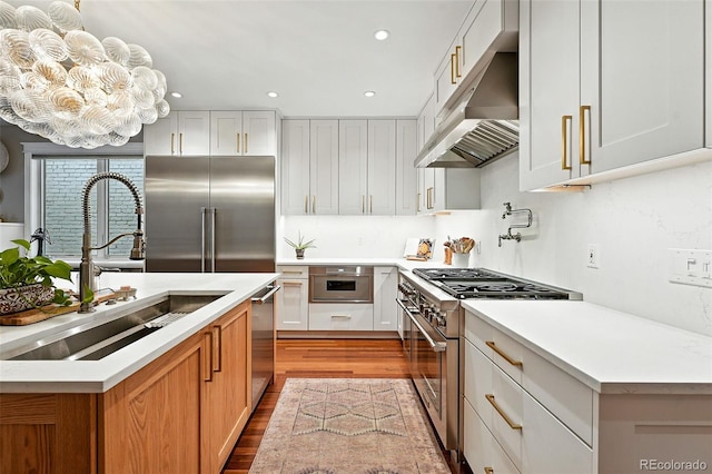 549 Milwaukee St, Denver, CO 80206 - kitchen featuring high quality appliances, under cabinet range hood, a chandelier, wood finished floors, and light countertops