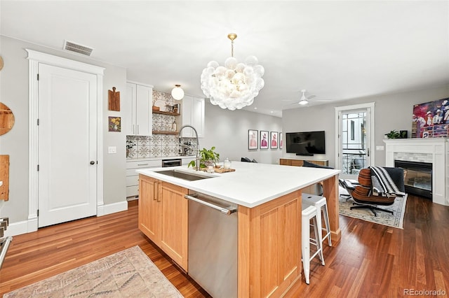 549 Milwaukee St, Denver, CO 80206 - kitchen with stainless steel dishwasher, wood finished floors, a center island with sink, open shelves, and light countertops