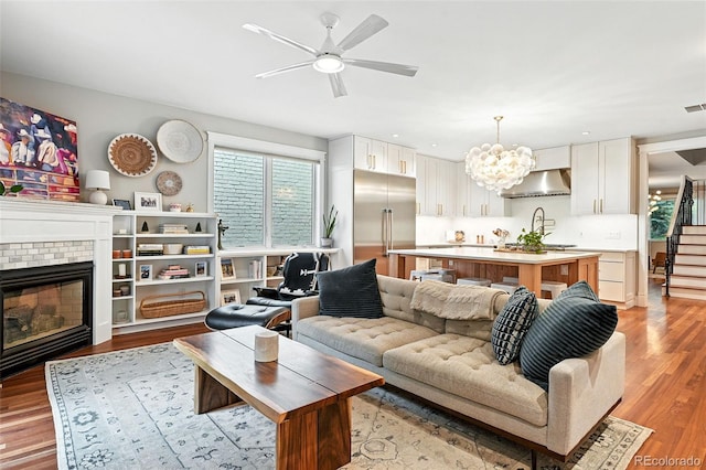 549 Milwaukee St, Denver, CO 80206 - living room featuring a brick fireplace, light wood-style flooring, a ceiling fan, and stairs