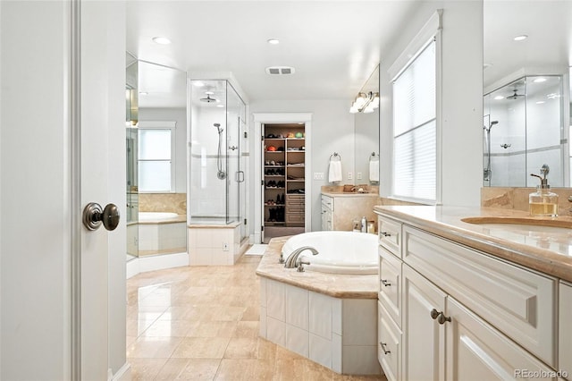 549 Milwaukee St, Denver, CO 80206 - full bathroom with a stall shower, two vanities, a garden tub, a walk in closet, and recessed lighting