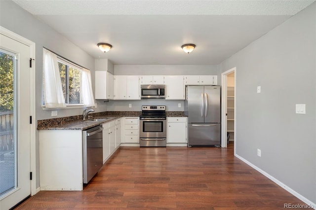 kitchen with white cabinets, appliances with stainless steel finishes, dark wood-type flooring, and a sink