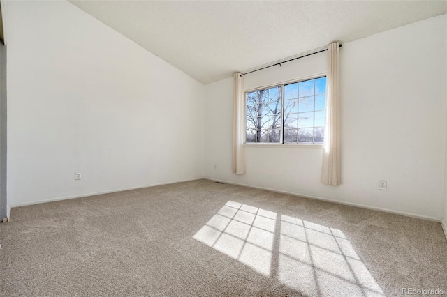 carpeted empty room featuring lofted ceiling and baseboards