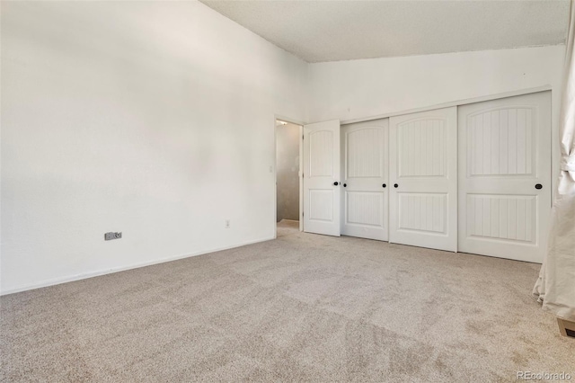 unfurnished bedroom featuring carpet, a closet, and high vaulted ceiling